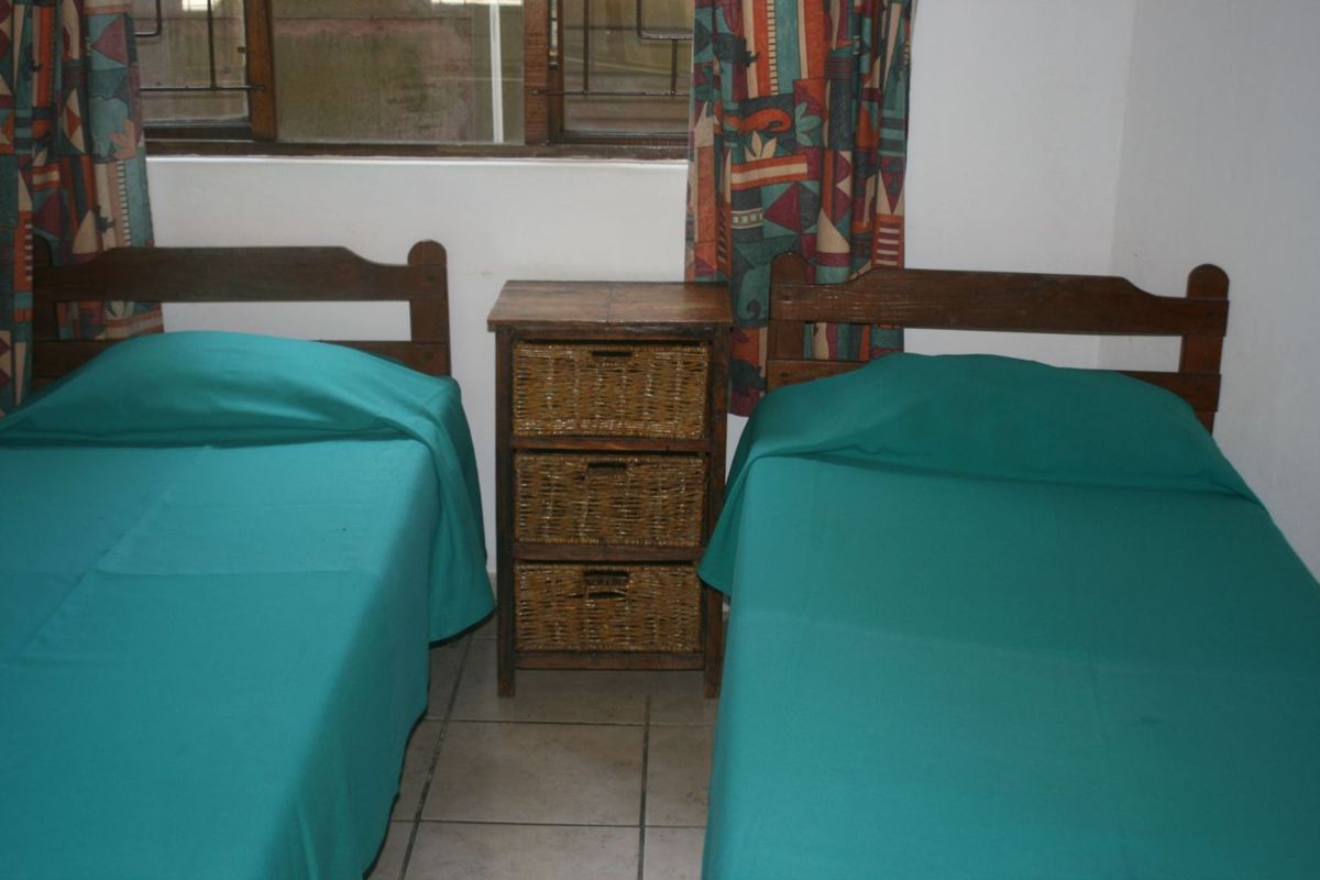 A bedroom featuring tiled flooring and a window with security bars, providing a functional space for accommodation.