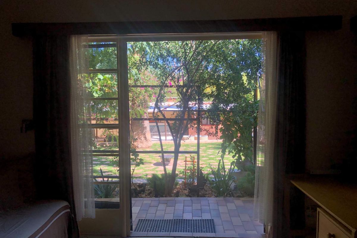 View from an interior room looking out through a sliding glass door onto a paved patio and private garden area.