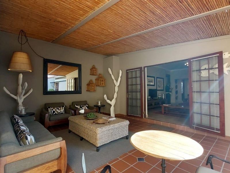 A covered patio area featuring terracotta floor tiles and a bamboo ceiling, providing a seamless transition to the interior living space through french doors.