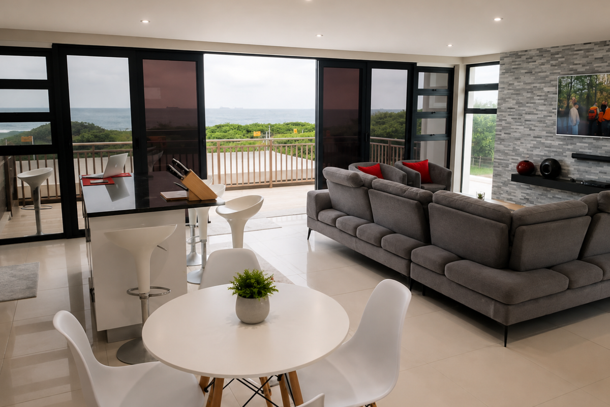 Modern open-plan living area featuring large sliding doors, a stone feature wall, and seamless access to a balcony with ocean views.