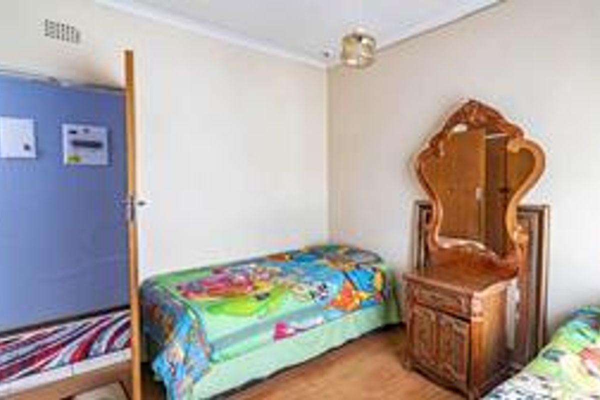 A functional bedroom featuring laminate flooring and a ceiling light fixture, with an integrated electrical distribution board located near the entrance.