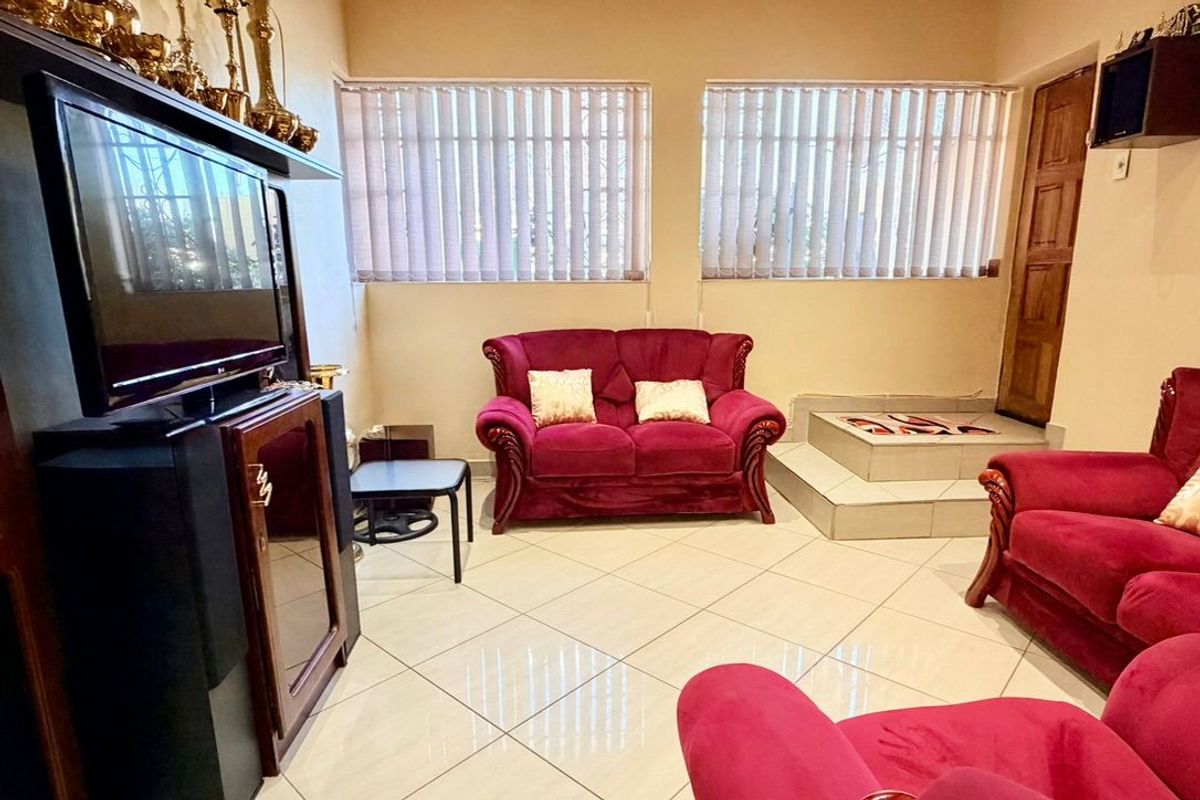 A living room featuring light-colored tiled flooring, vertical window blinds, and a unique raised platform area.