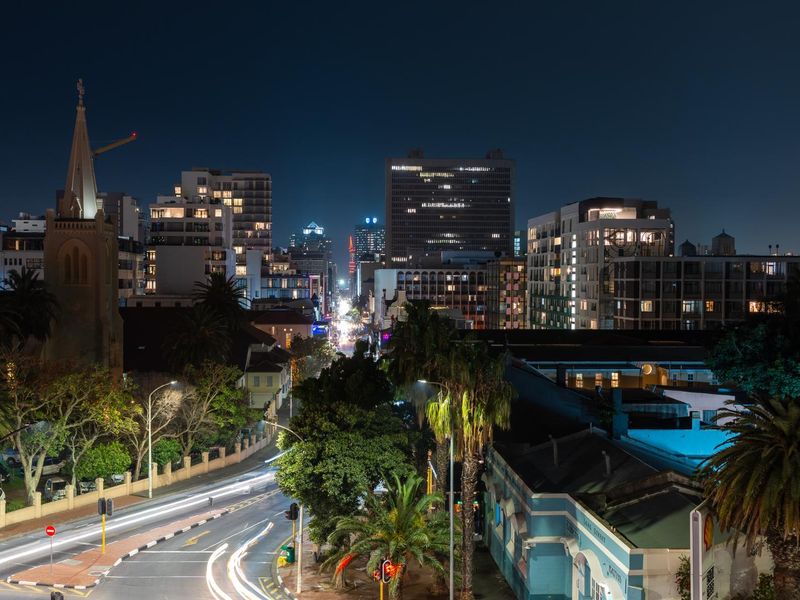 A night-time elevated view overlooking the surrounding city skyline, street traffic, and urban landscape.