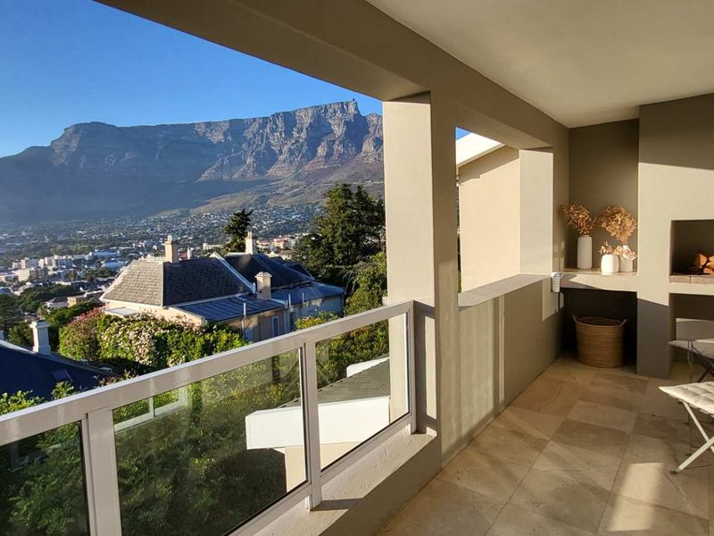 Covered balcony featuring a built-in braai, glass balustrade, and panoramic mountain views.