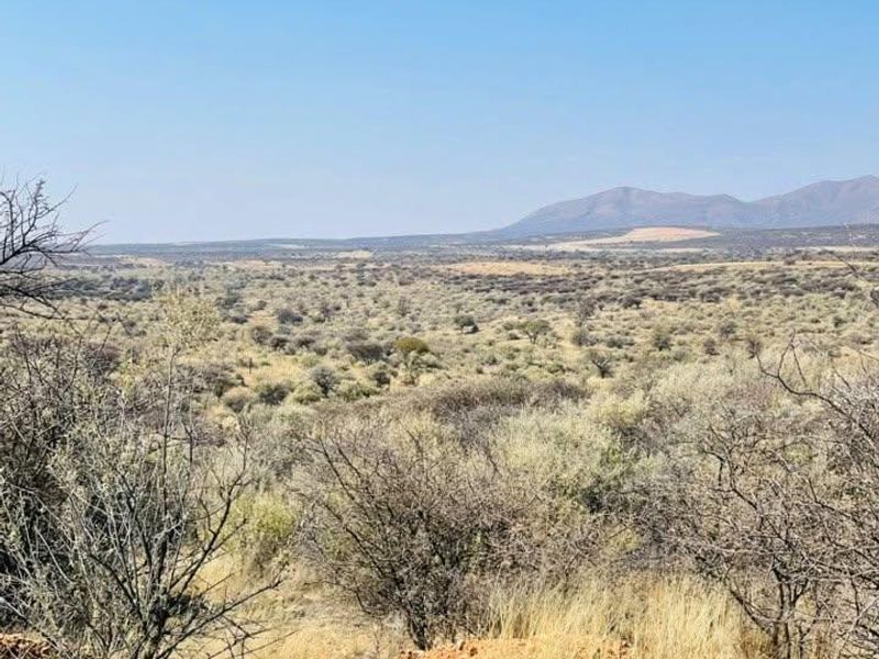 A scenic, elevated view of the expansive natural landscape and distant mountain range, showcasing the property's open terrain.