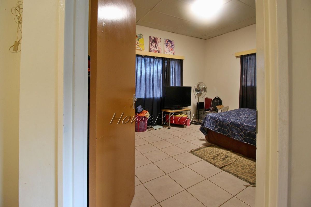 A bedroom featuring tiled flooring and standard window treatments, viewed from the doorway.