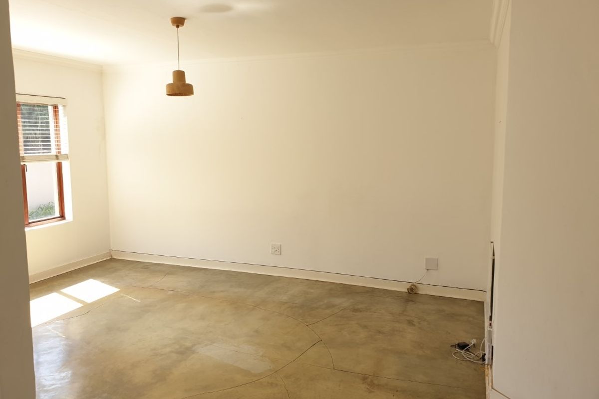 A bright, empty bedroom featuring polished concrete floors, neutral walls, and a window with fitted blinds, offering a clean canvas for personalization.
