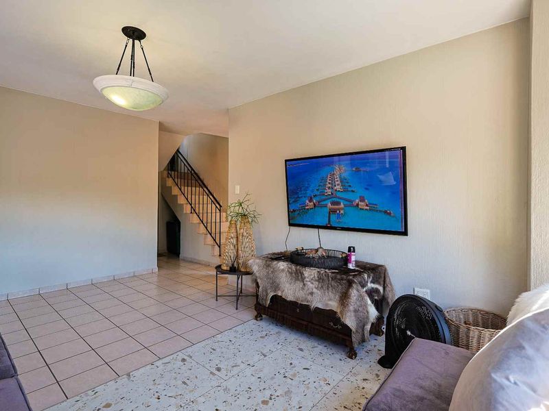 Living room area featuring a staircase with a wrought iron balustrade, tiled flooring, and a mix of ceramic and terrazzo floor finishes.