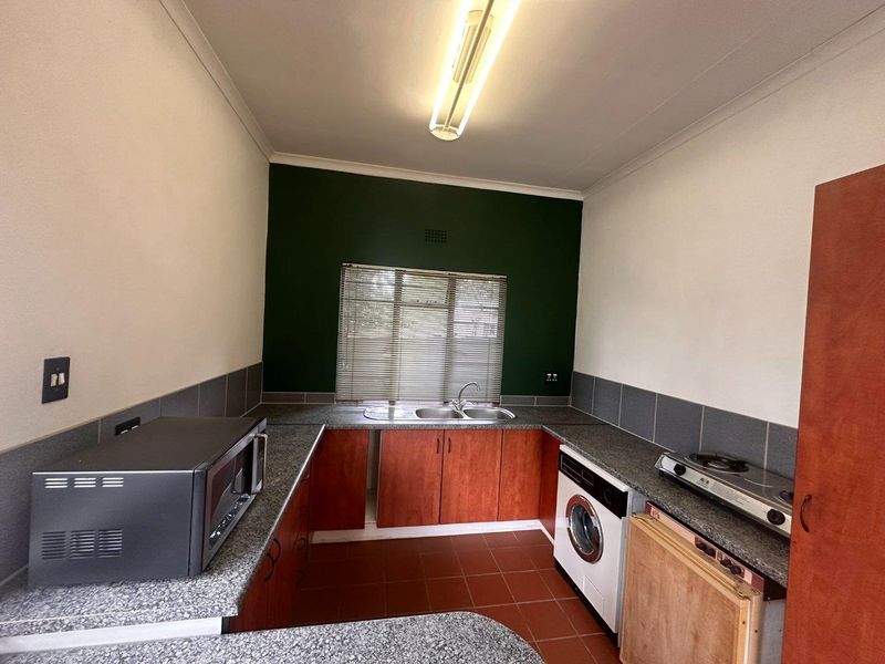 Functional kitchen featuring laminate cabinetry, granite-look countertops, stainless steel sink, and tiled flooring, offering a practical layout for daily meal preparation.