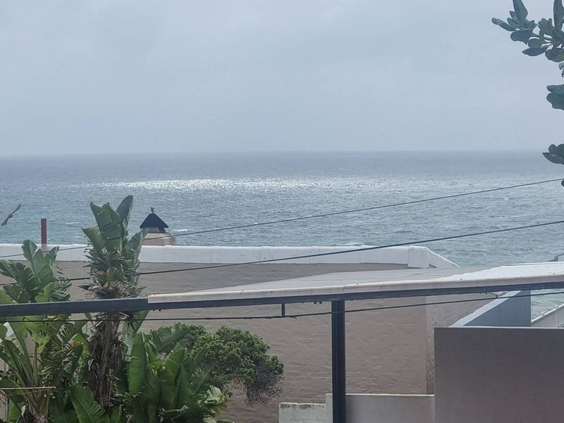 A scenic view of the ocean captured from an elevated position, showcasing the coastal horizon and surrounding residential rooftops.