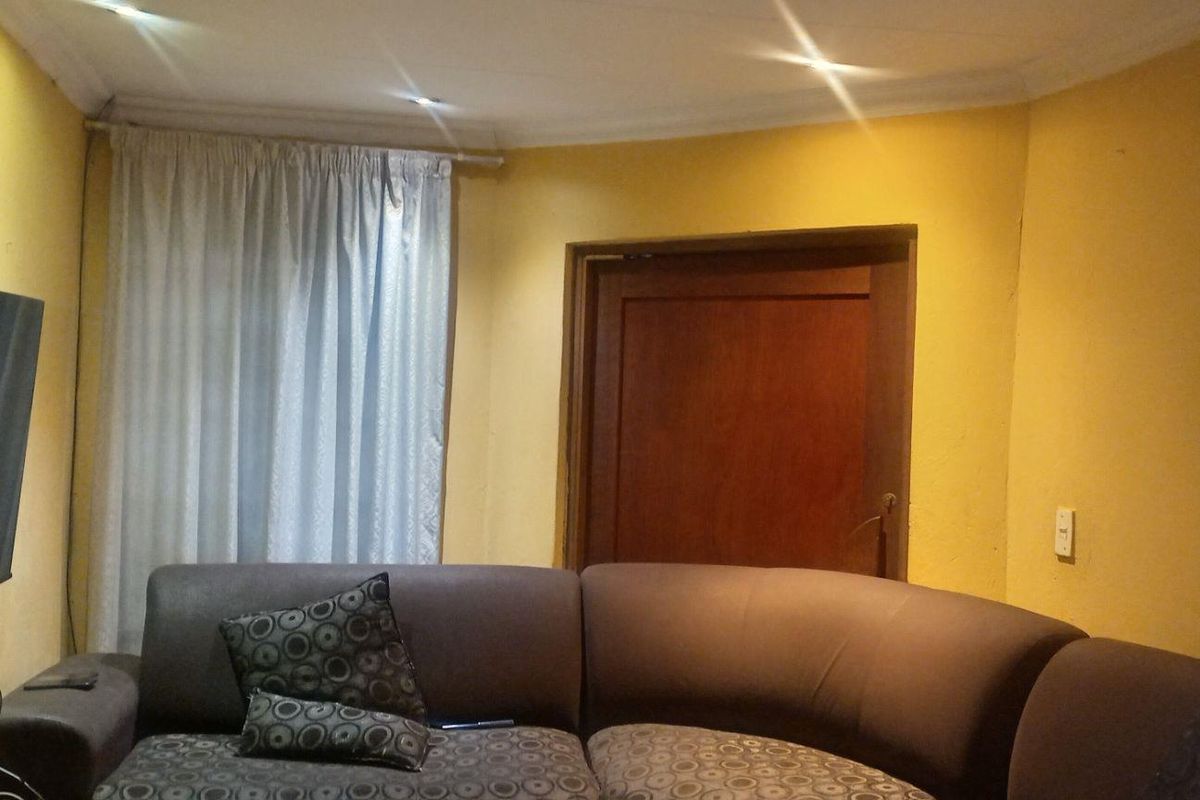 A living room featuring yellow walls, a wooden door, and recessed ceiling lighting.