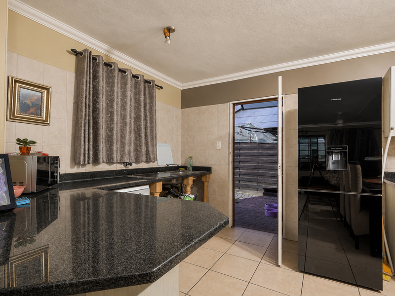 Kitchen featuring granite countertops, tiled backsplash, and direct access to an outdoor patio area.