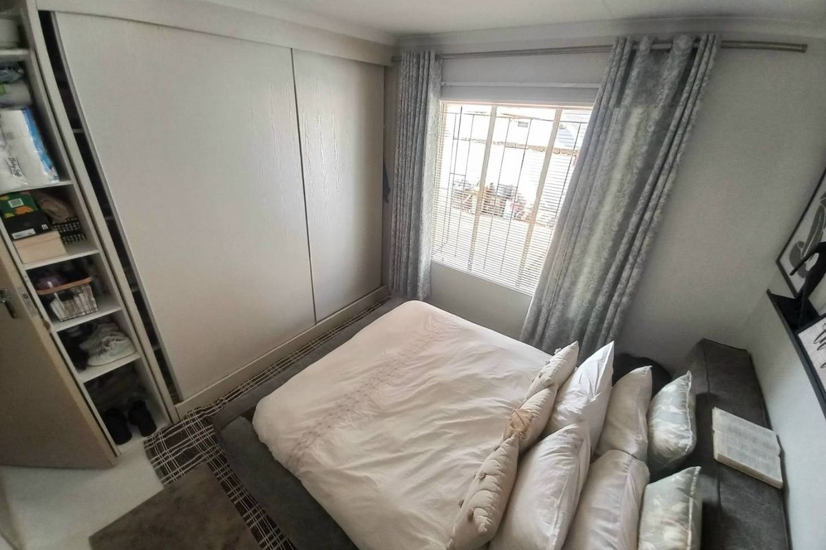 A well-maintained bedroom featuring built-in sliding door wardrobes and a window with security bars, offering a clean and functional living space.