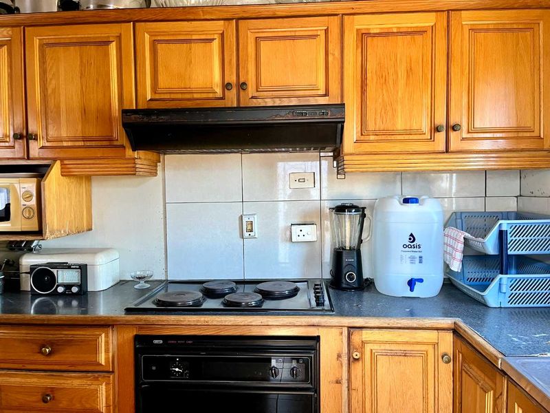 A functional kitchen featuring traditional wooden cabinetry, a built-in oven with electric hob, and a tiled backsplash.