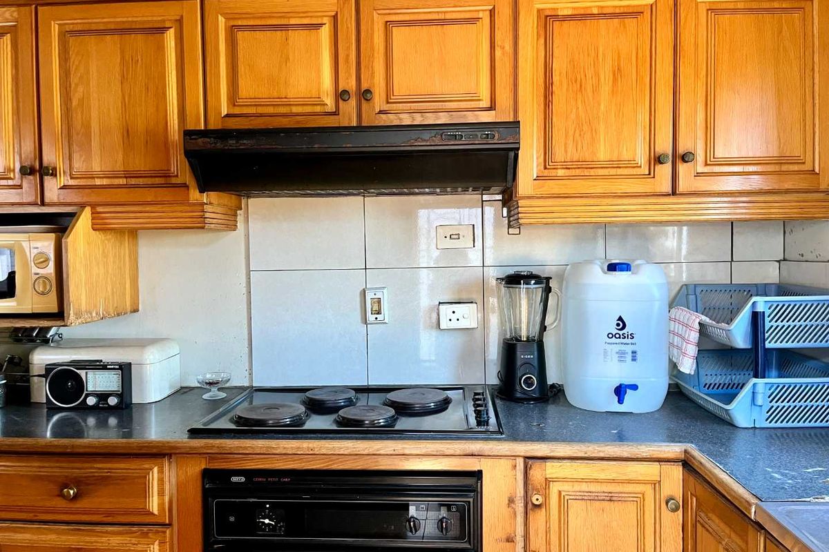 A functional kitchen featuring traditional wooden cabinetry, a built-in oven with electric hob, and a tiled backsplash.