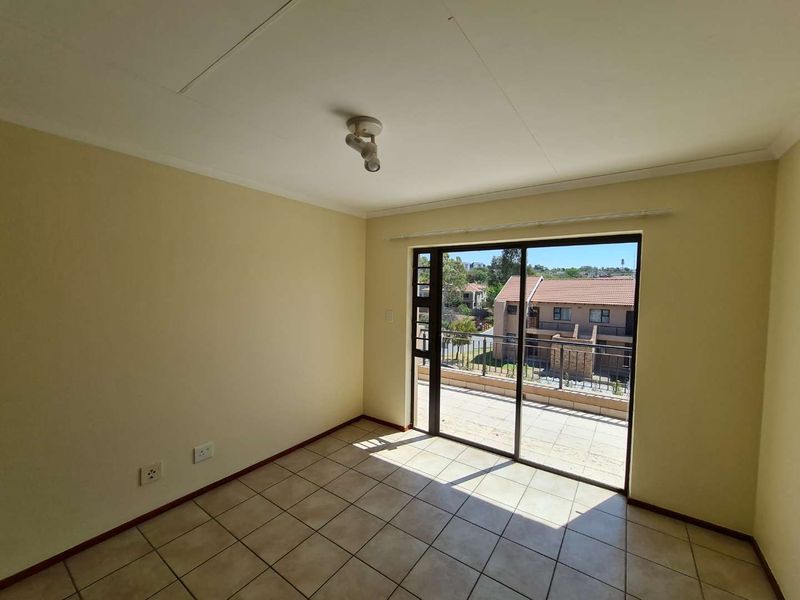 An empty bedroom featuring tiled flooring and a large sliding glass door that provides direct access to a private balcony.