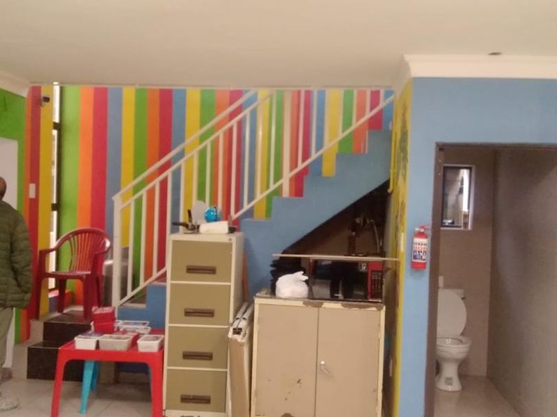 Hallway area featuring a staircase with metal balustrade, tiled flooring, and an adjacent small bathroom with a toilet.