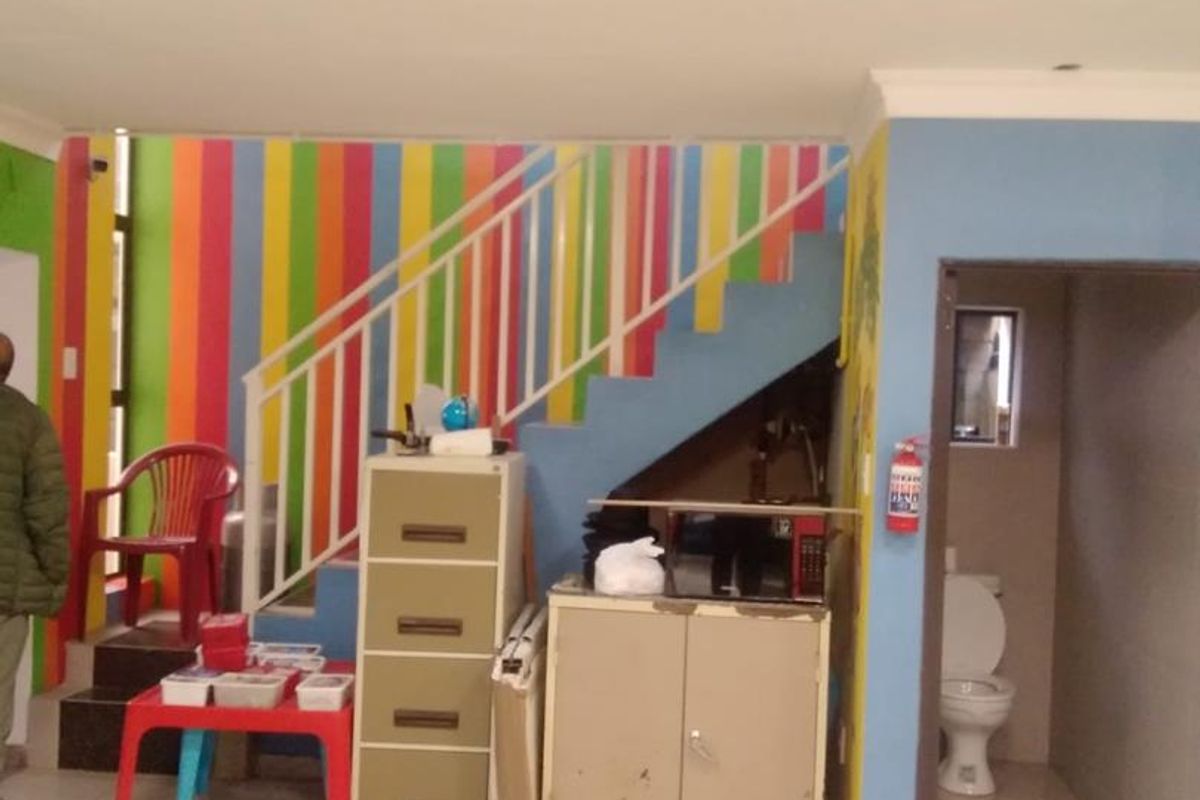 Hallway area featuring a staircase with metal balustrade, tiled flooring, and an adjacent small bathroom with a toilet.