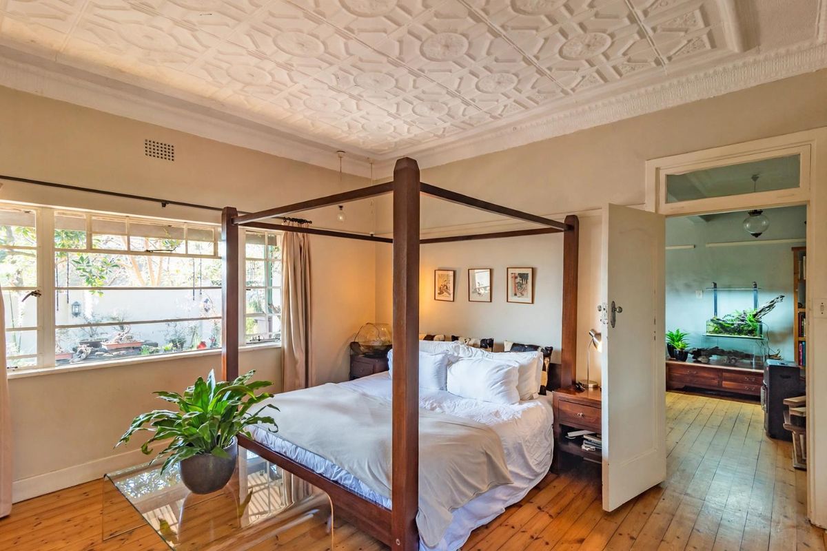 Spacious bedroom featuring a decorative pressed metal ceiling, polished timber flooring, and large casement windows allowing for natural light.