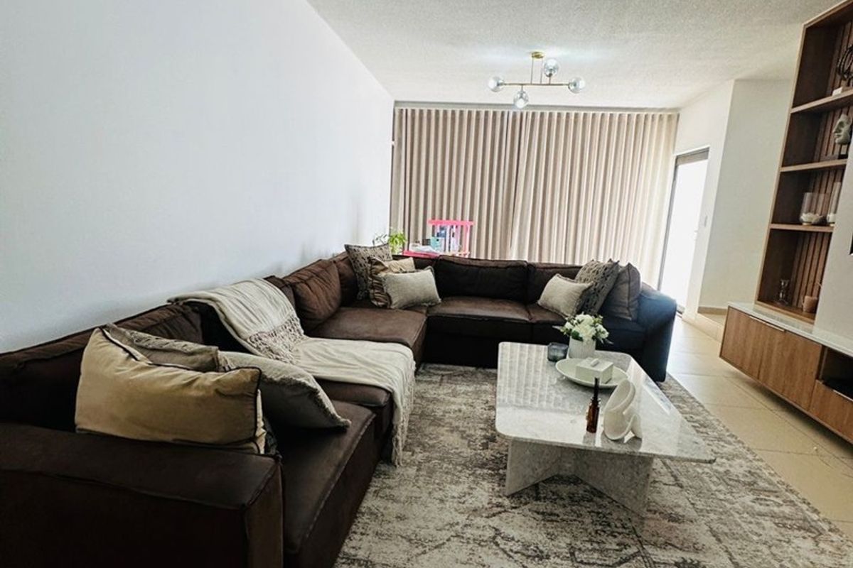 Spacious living room featuring tiled flooring, a custom built-in shelving unit, and modern lighting, creating a comfortable and functional living space.