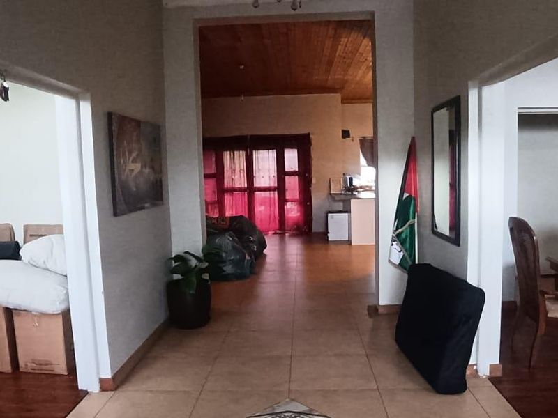 A central hallway featuring tiled flooring and a wooden ceiling, providing access to adjacent living and dining areas.