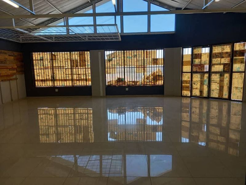 Spacious open-plan industrial unit featuring polished tiled flooring, exposed steel roof structure, and high-level windows providing ample natural light.
