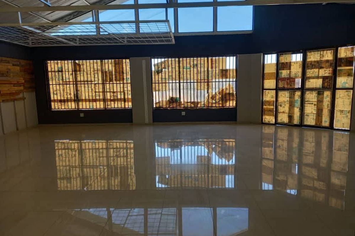 Spacious open-plan industrial unit featuring polished tiled flooring, exposed steel roof structure, and high-level windows providing ample natural light.