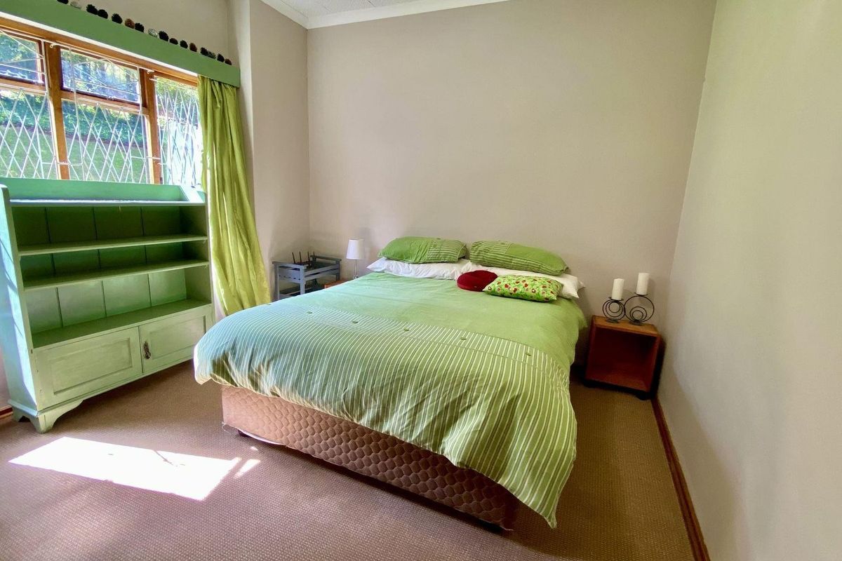 A bedroom featuring carpeted flooring and a large window with security bars, providing natural light to the space.