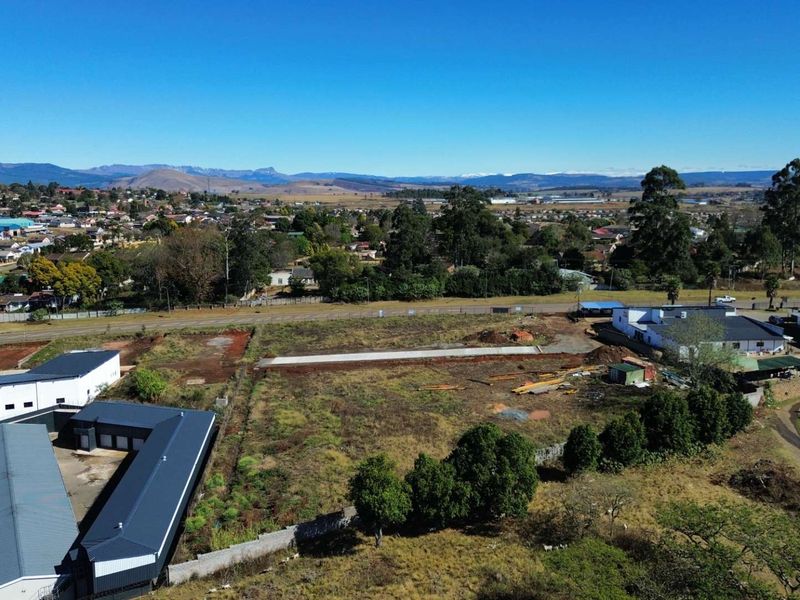Aerial view of a vacant commercial land plot featuring a concrete foundation slab, surrounding boundary walls, and adjacent commercial buildings in a developed area.