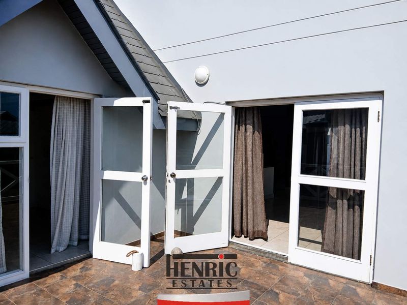A covered patio area featuring tiled flooring and double glass doors providing access to the interior living space.