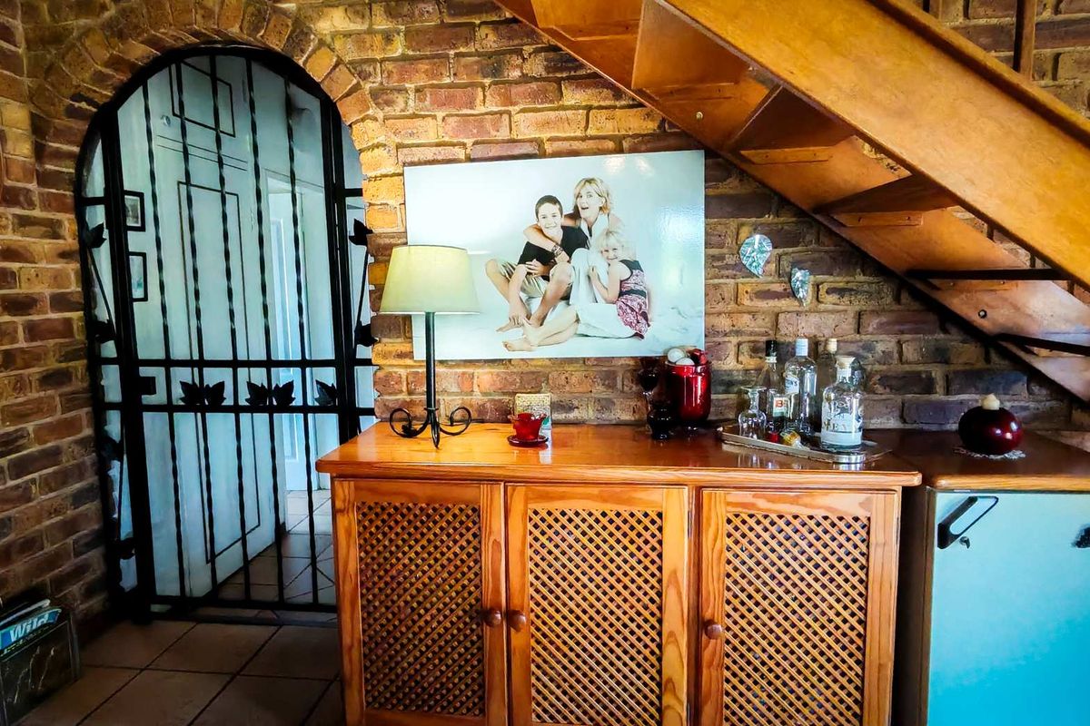 Interior view featuring exposed brick walls, a wooden staircase, and a decorative wrought iron security gate leading to an adjacent room.