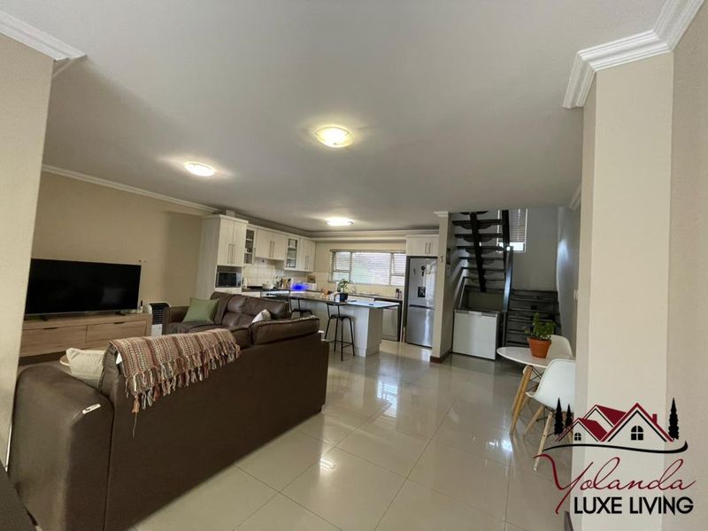 Spacious open-plan living area featuring a modern kitchen with island, tiled flooring, and a staircase leading to the upper level.