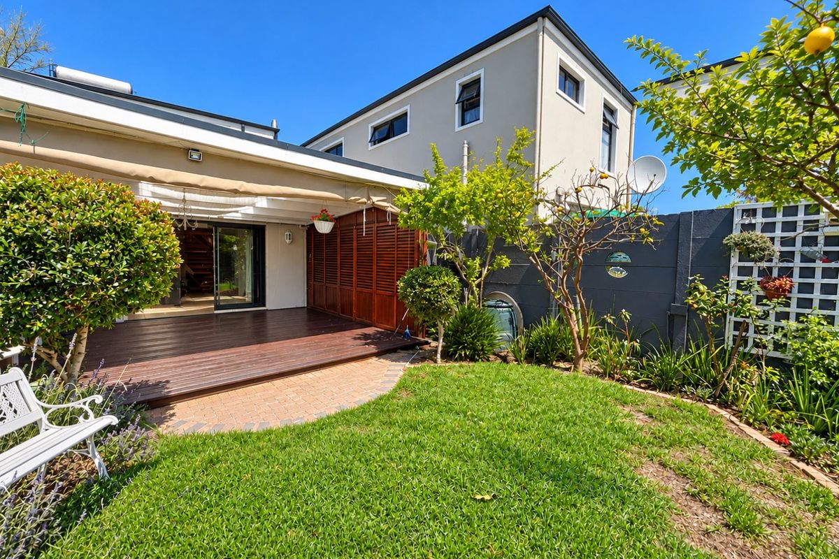 A well-maintained rear garden featuring a timber deck, retractable awning, and established landscaping, providing a private outdoor living space.
