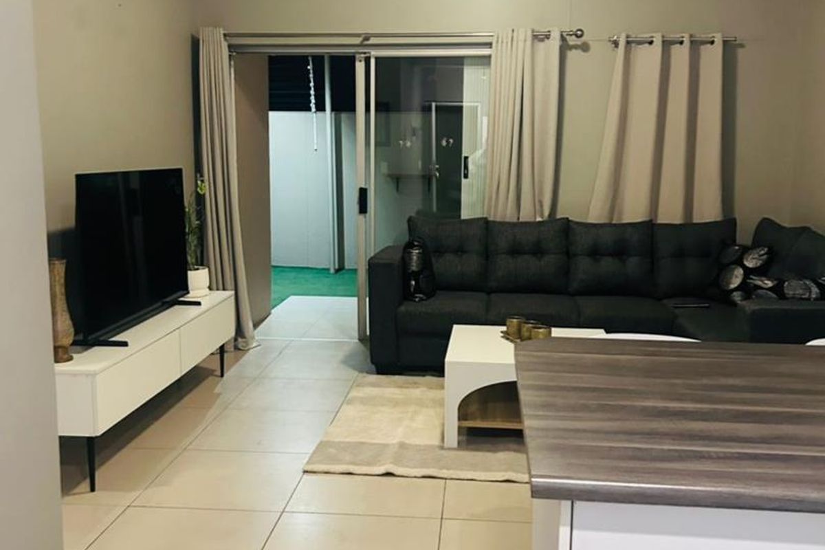 Open plan living area featuring tiled flooring, a split-system air conditioner, and direct access to an outdoor patio through sliding glass doors.