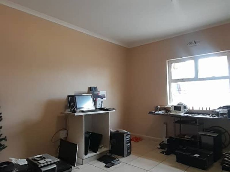 A bedroom featuring tiled flooring and a window, currently utilized as a workspace.