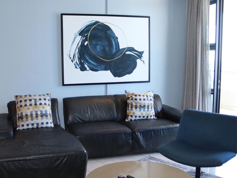 A well-lit living room featuring tiled flooring and a large sliding glass door providing access to the exterior.