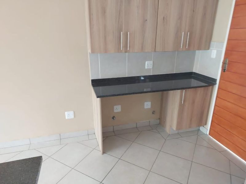 A clean and functional laundry area featuring built-in wood-finish cabinetry, a durable granite countertop, and tiled flooring with dedicated plumbing connections.