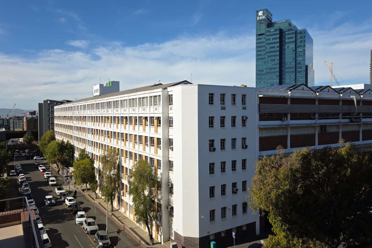 An aerial view of a multi-story apartment building facade situated along a city street, showcasing the exterior architecture and urban surroundings.