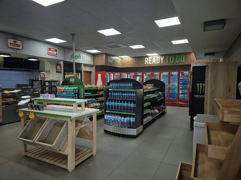 A well-maintained commercial retail space featuring tiled flooring, recessed ceiling lighting, and integrated refrigeration units for food and beverage display.