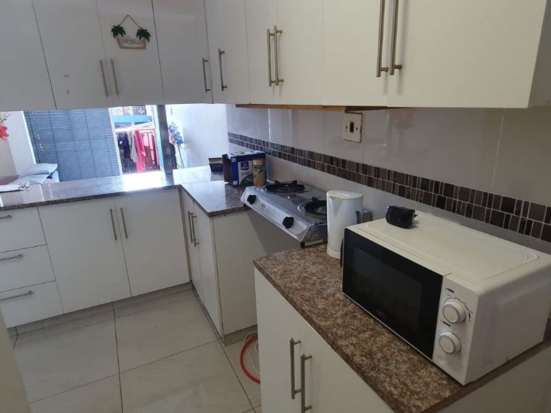 A functional kitchen featuring white cabinetry, laminate countertops, a tiled backsplash, and a gas cooktop, offering a practical layout for daily meal preparation.