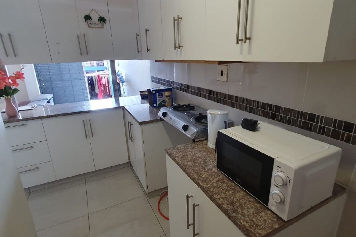 A functional kitchen featuring white cabinetry, laminate countertops, a tiled backsplash, and a gas cooktop, offering a practical layout for daily meal preparation.