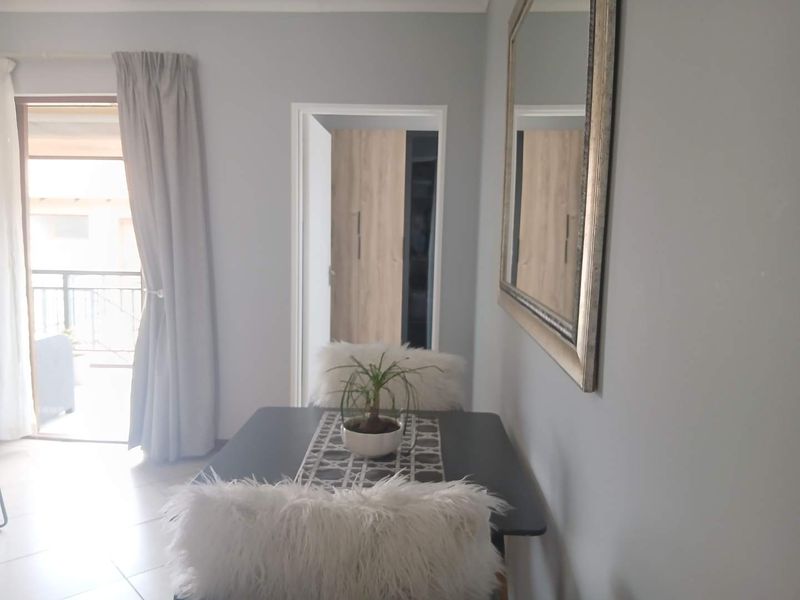 A bright dining area featuring tiled flooring, a sliding glass door leading to a balcony, and access to a built-in cupboard.