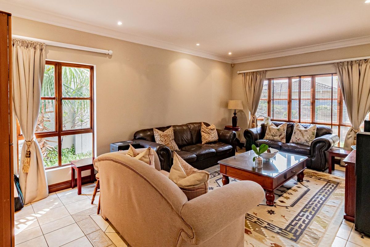 A comfortable living room featuring tiled flooring, recessed ceiling lighting, and large windows that provide natural light.