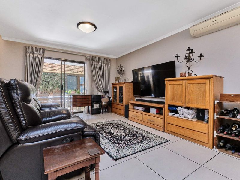 A comfortable living room featuring tiled flooring, a wall-mounted air conditioning unit, and a sliding glass door providing access to the outdoor area.