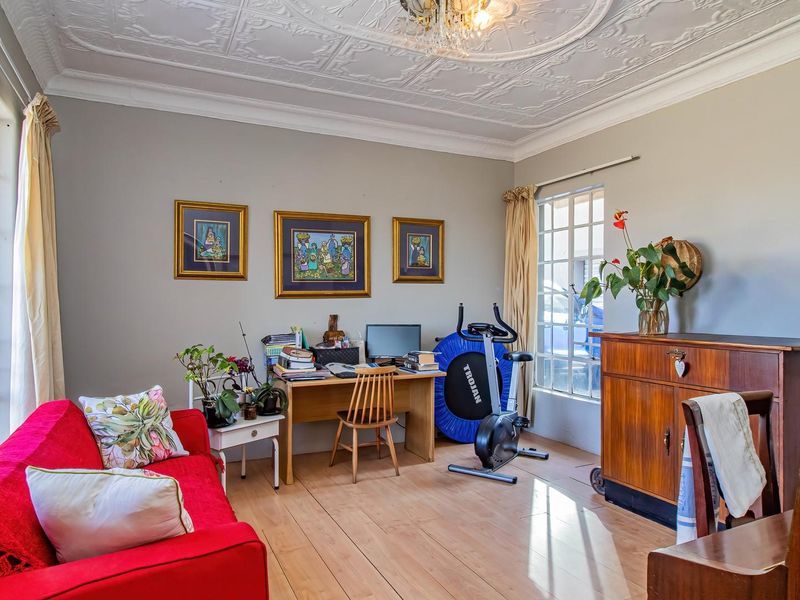 A bright living room featuring classic wooden flooring and an ornate pressed metal ceiling, offering a characterful space with ample natural light.
