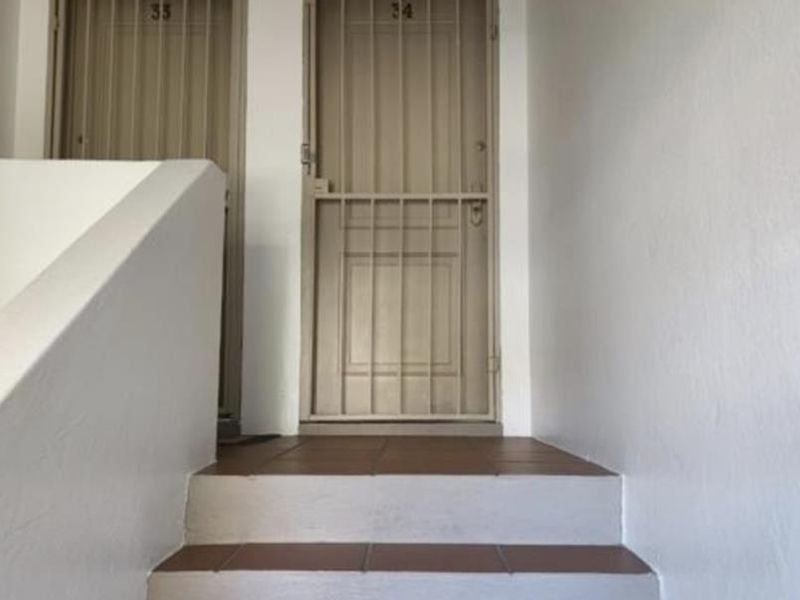 An apartment entrance area featuring a tiled staircase leading to two secure unit doors with fitted security gates.