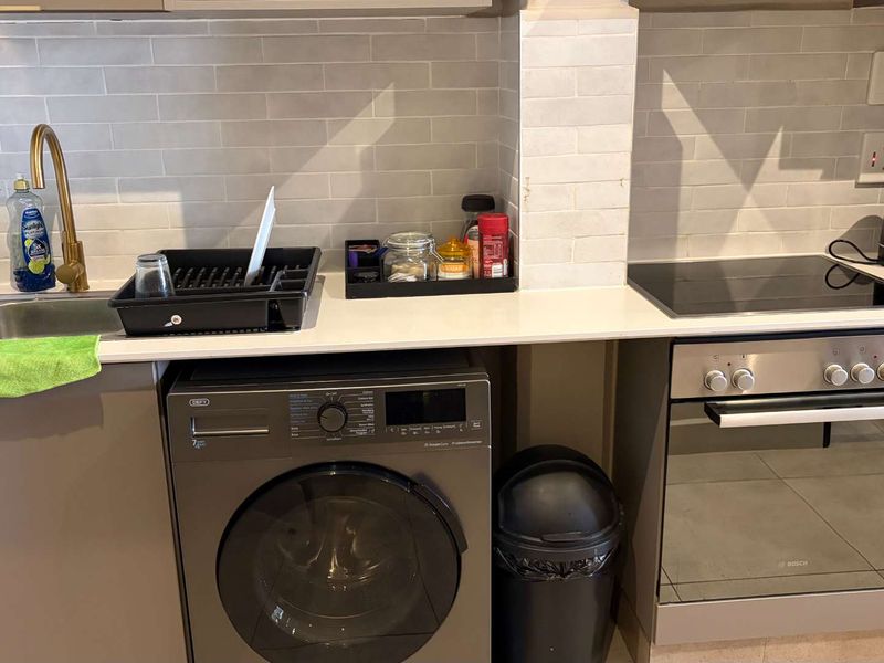 Modern kitchen featuring a subway tile backsplash, quartz countertops, brass faucet, and integrated appliances including a built-in oven and electric hob.