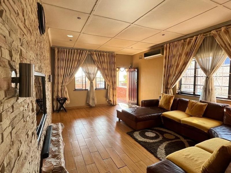 Spacious living room featuring a textured stone cladding feature wall, tiled flooring, and a split-system air conditioner, offering a comfortable and functional living space.