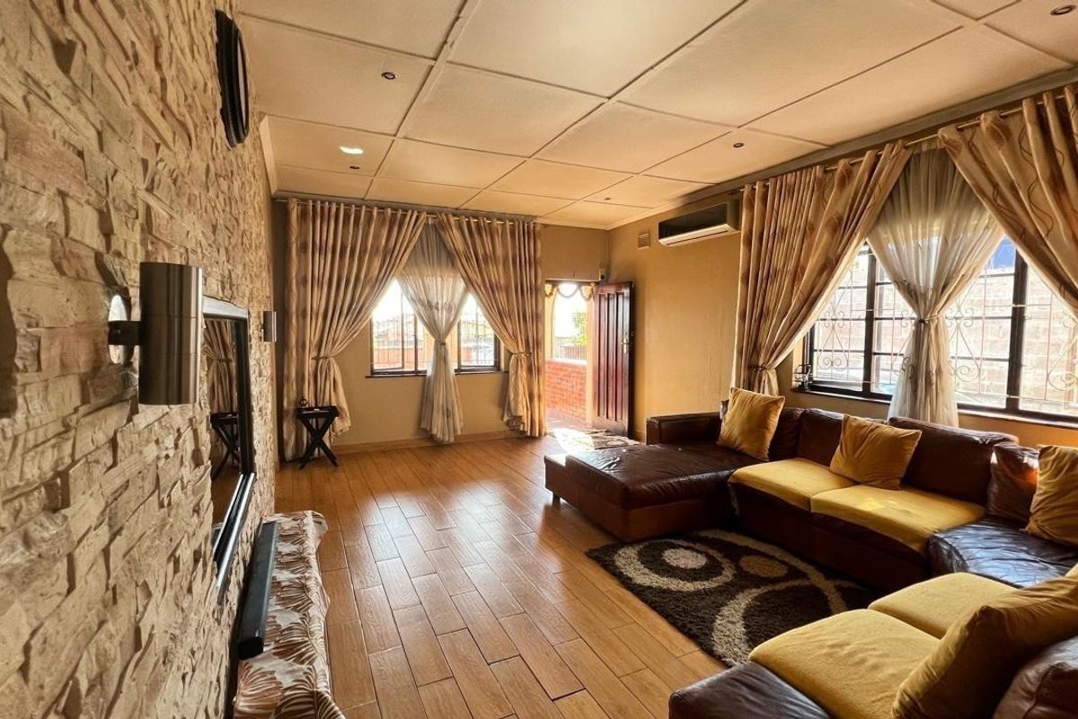 Spacious living room featuring a textured stone cladding feature wall, tiled flooring, and a split-system air conditioner, offering a comfortable and functional living space.