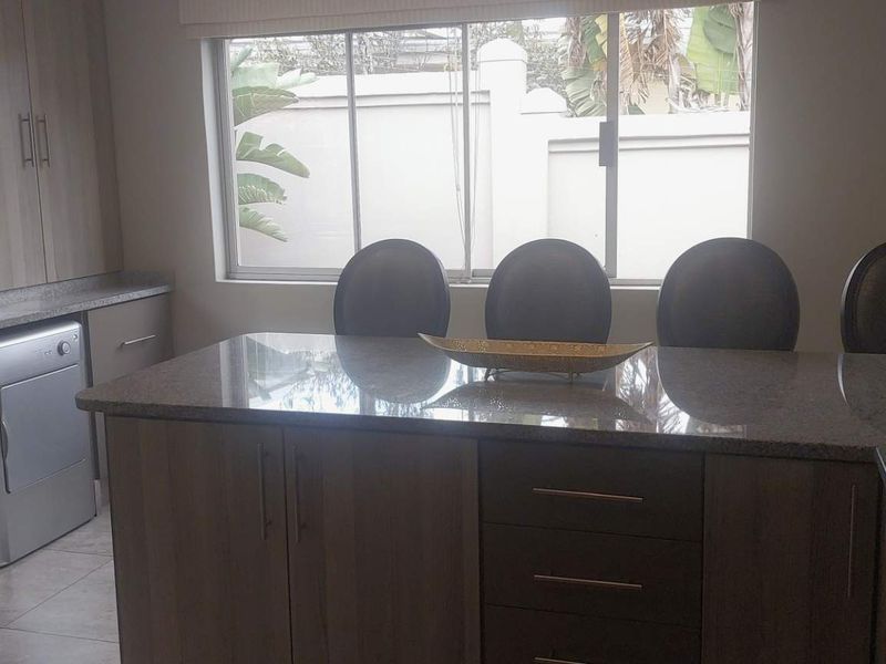 A functional kitchen featuring granite countertops, ample built-in cabinetry, and integrated under-counter laundry appliances, providing a practical and well-organized workspace.